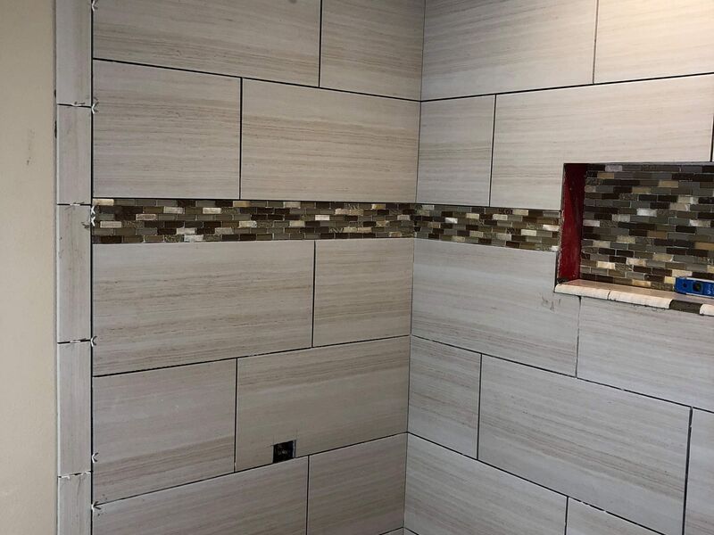 Shower tile installation with mosaic accent band and niche