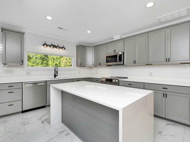 Completed modern kitchen remodel with gray cabinetry and marble-look flooring