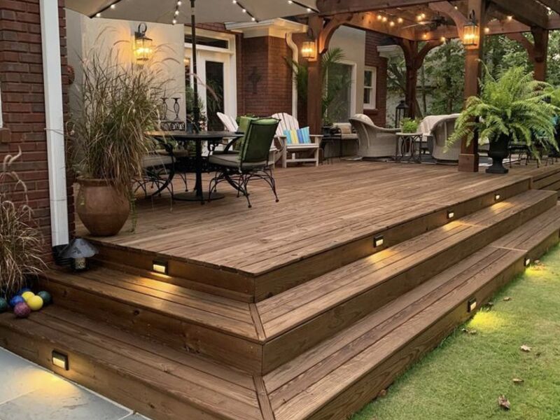 Pergola-covered deck with string lighting by ArchAngel Construction Services