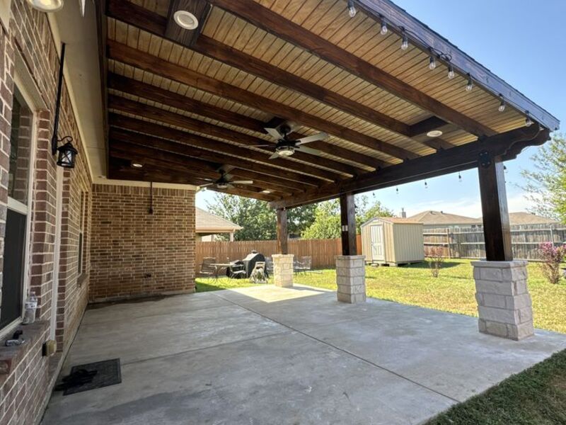 Covered patio with ceiling fans and stone columns by ArchAngel Construction Services