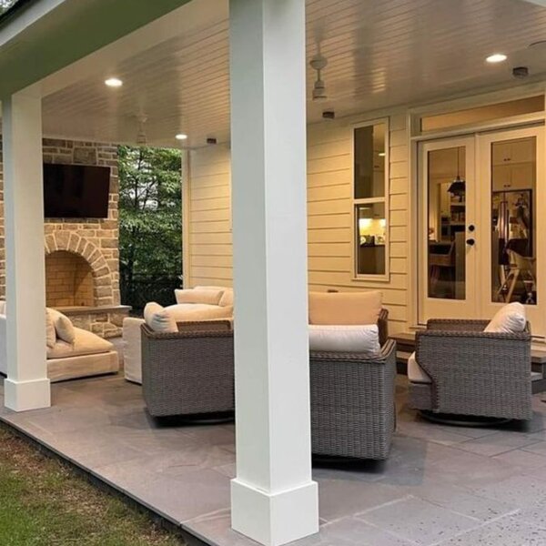Covered outdoor patio with stone fireplace and seating area by ArchAngel Construction Services